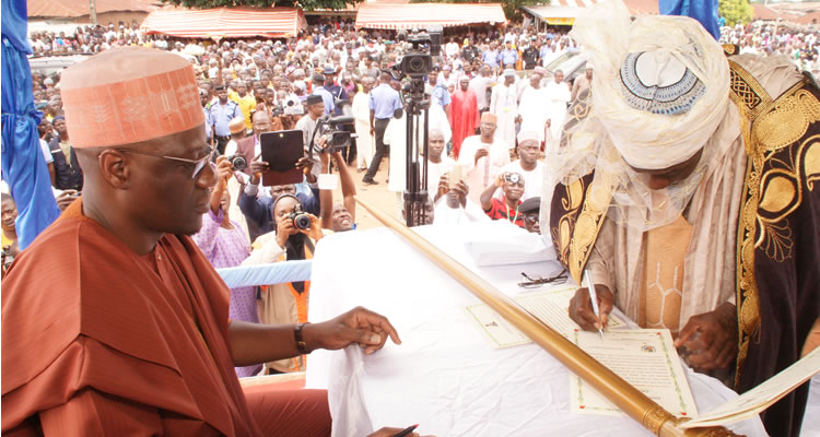 Emir of Ilesha Baruba, Prof. Halidu Abubakar (right) Signing the dotted line while the Kwara State Governor, Dr. Abdulfatah Ahmed watches during the presentation of 2nd Class Staff of Office at Ilesha Baruba in Baruten LGA...Wednesday.